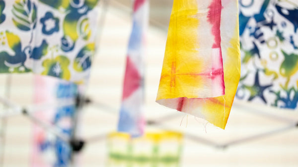 Textile stencil work with a wooden spatula; dye-pouring is a separate stage.