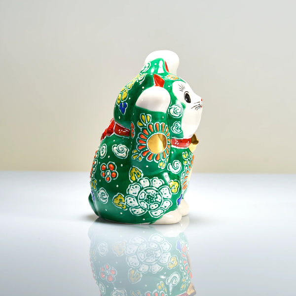 Side view of the deep green Kutani maneki neko, showing round gold-tone accents, raised white mori details and scrolling motifs