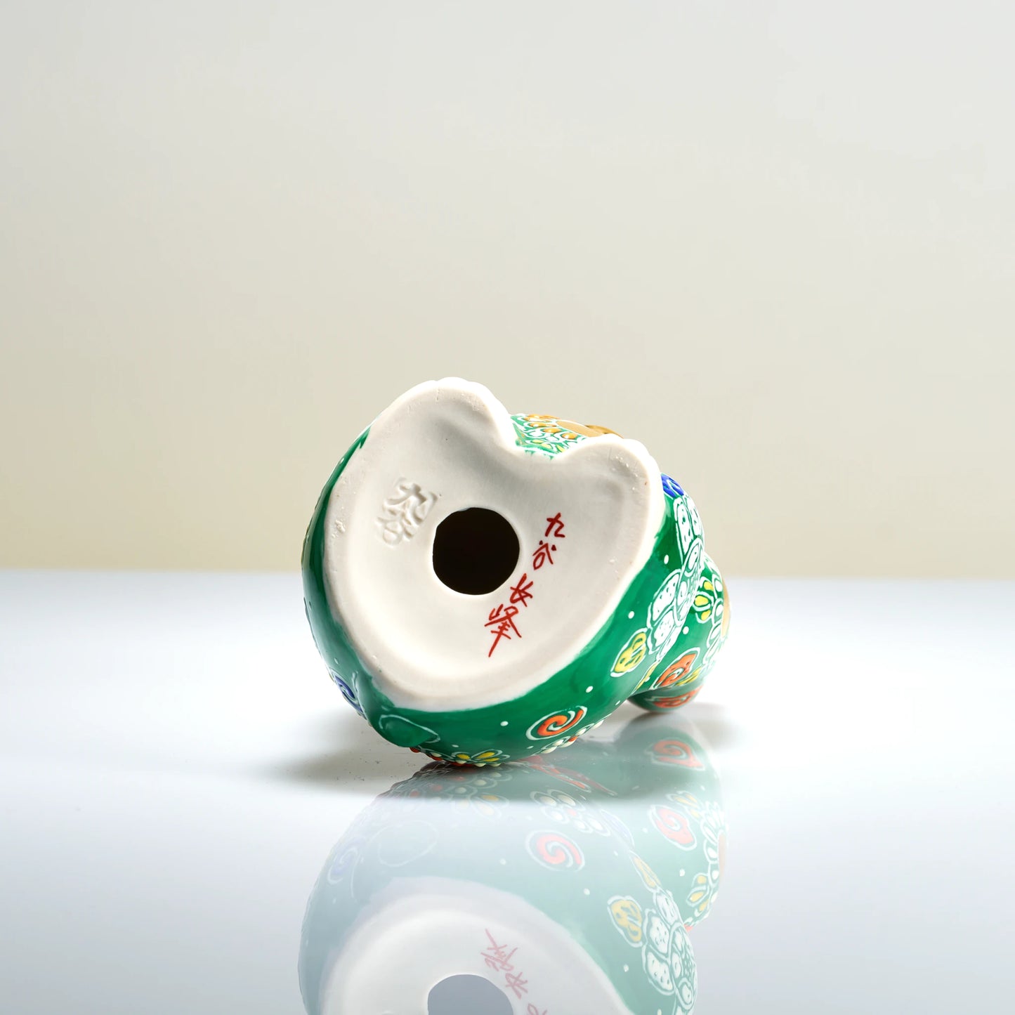 Bottom base view of the Kutani porcelain cat showing the red hand-painted artist signature and impressed Kutani foot mark.