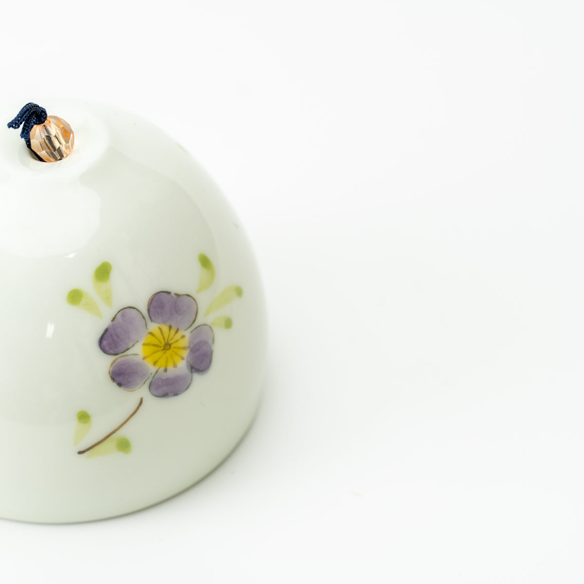 Close-up of a purple flower with a yellow center on the pale Arita wind-chime bell.