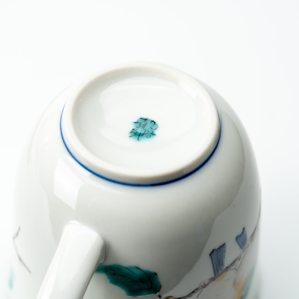 Underside of the Mejiro bird mug showing a small green mark and blue line around the foot.