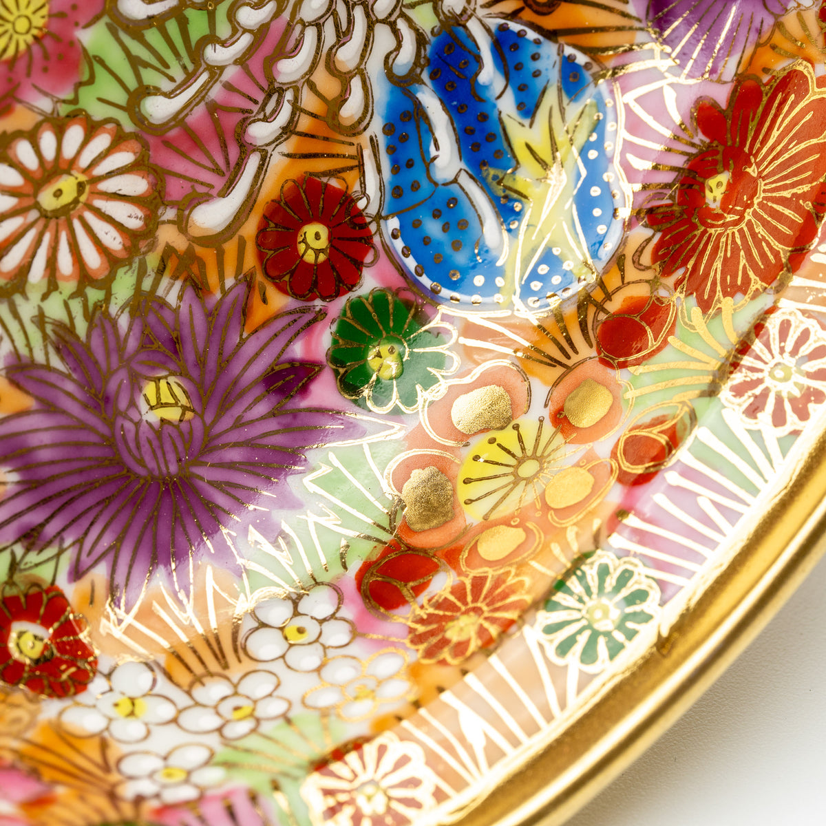 Detail of blue, purple and red flowers outlined in gold color inside the Kinhanazume bowl.