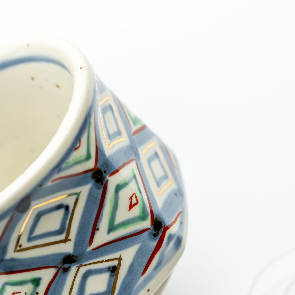 Detail of the demitasse cup's multicolored diamond pattern and blue line inside the rim.