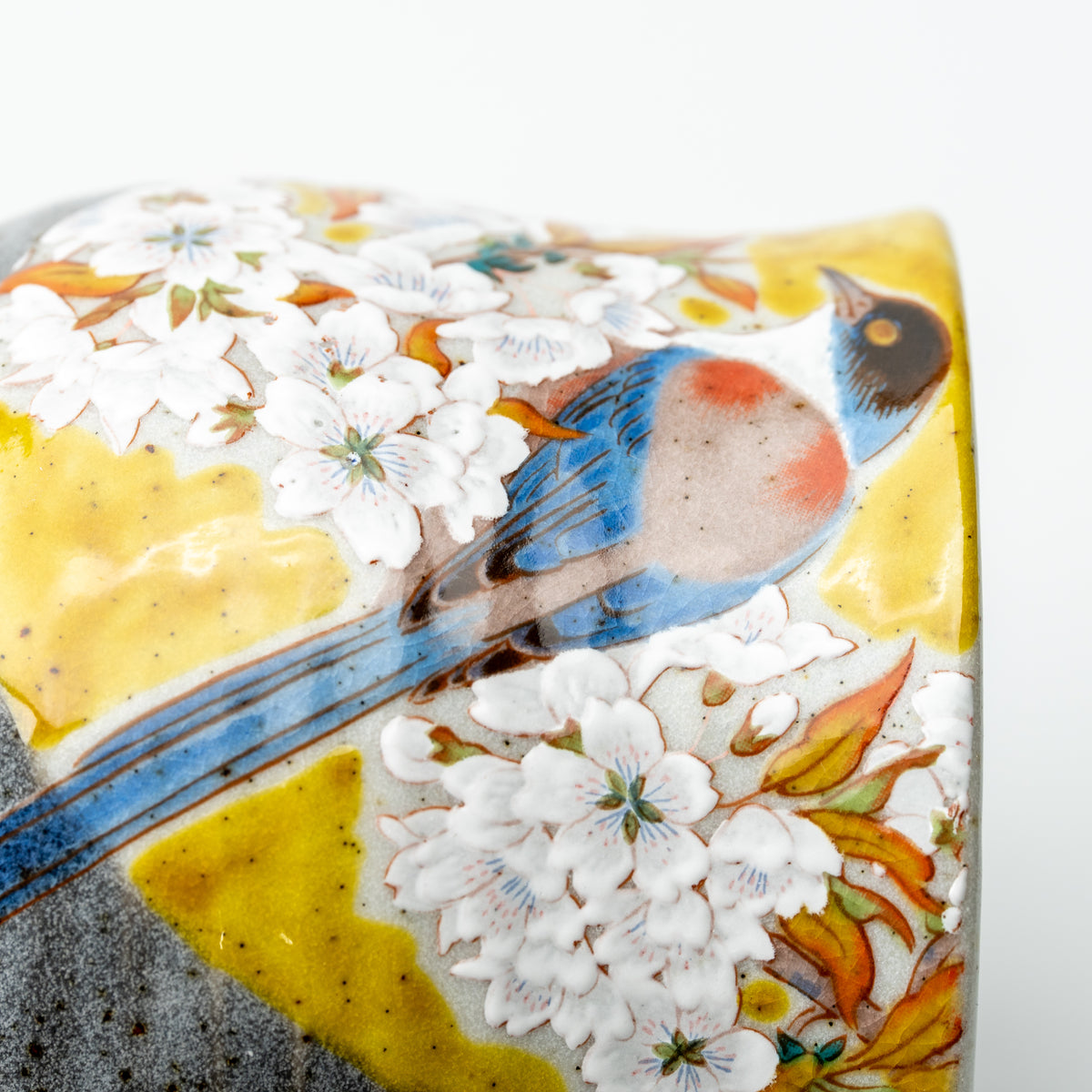Close-up of a long-tailed bird and white cherry blossoms on the yellow-accented Kutani mug.