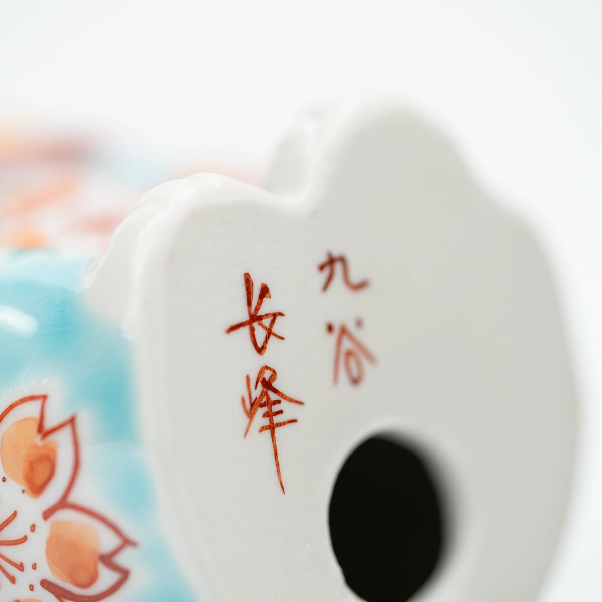 Close-up of the red Kutani Chōhō mark beneath the lucky cat