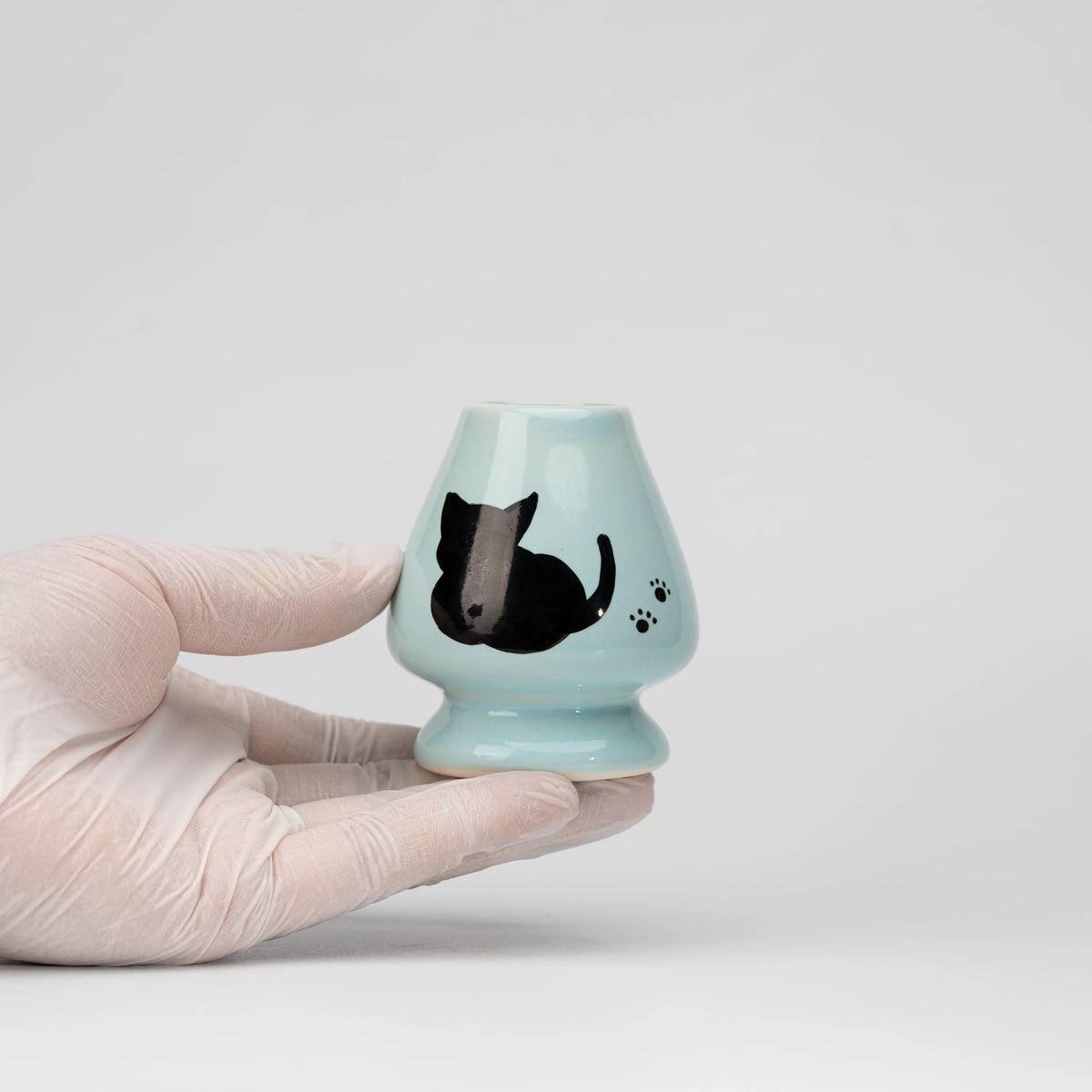 Pale blue cat whisk holder, held in a hand to show scale.