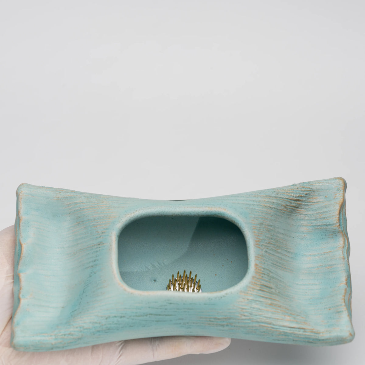 Pale blue mini ikebana vase, held in a hand to show scale.