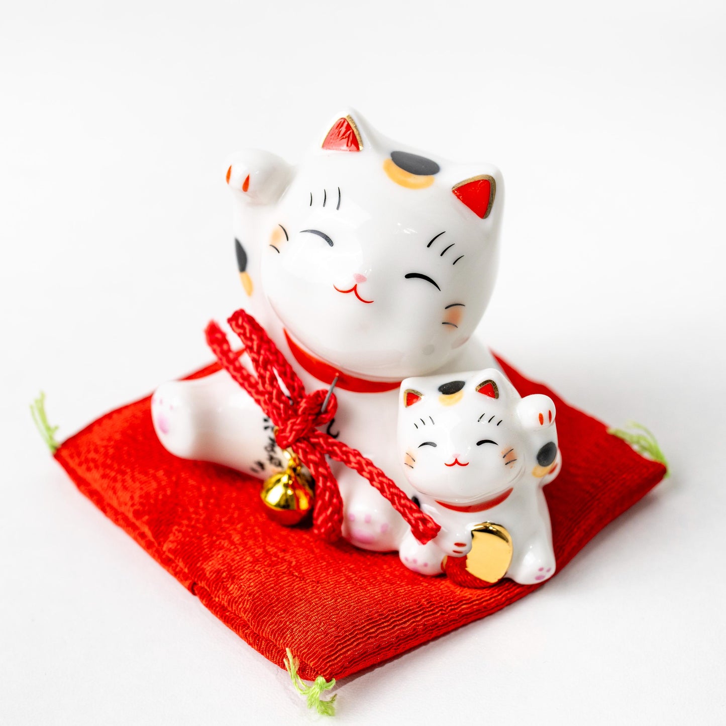 Angled view of mother and kitten Maneki Neko on red cushion