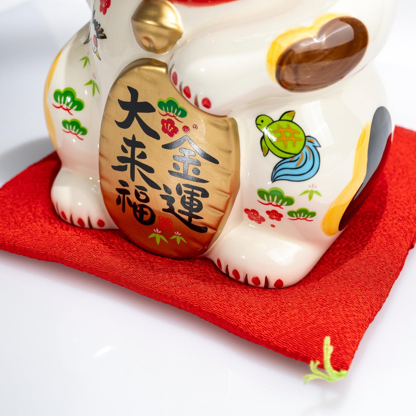 Rear angle of ceramic Maneki Neko on red base