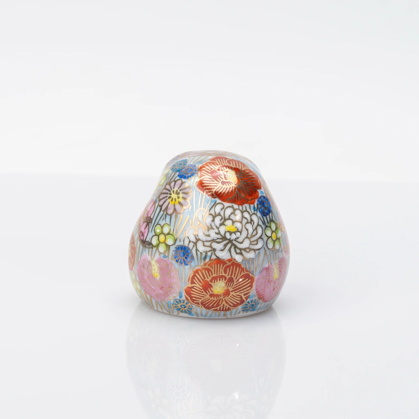 Rear view of the blue Kutani Daruma fully covered with multicolored Hanazume floral decoration