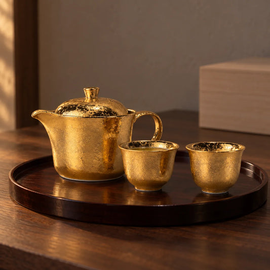 Arita gold tea set with teapot and two small sencha cups on a dark lacquer tray