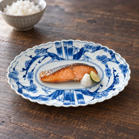 Arita pine, bamboo and plum oval porcelain platter holding a small piece of grilled salmon