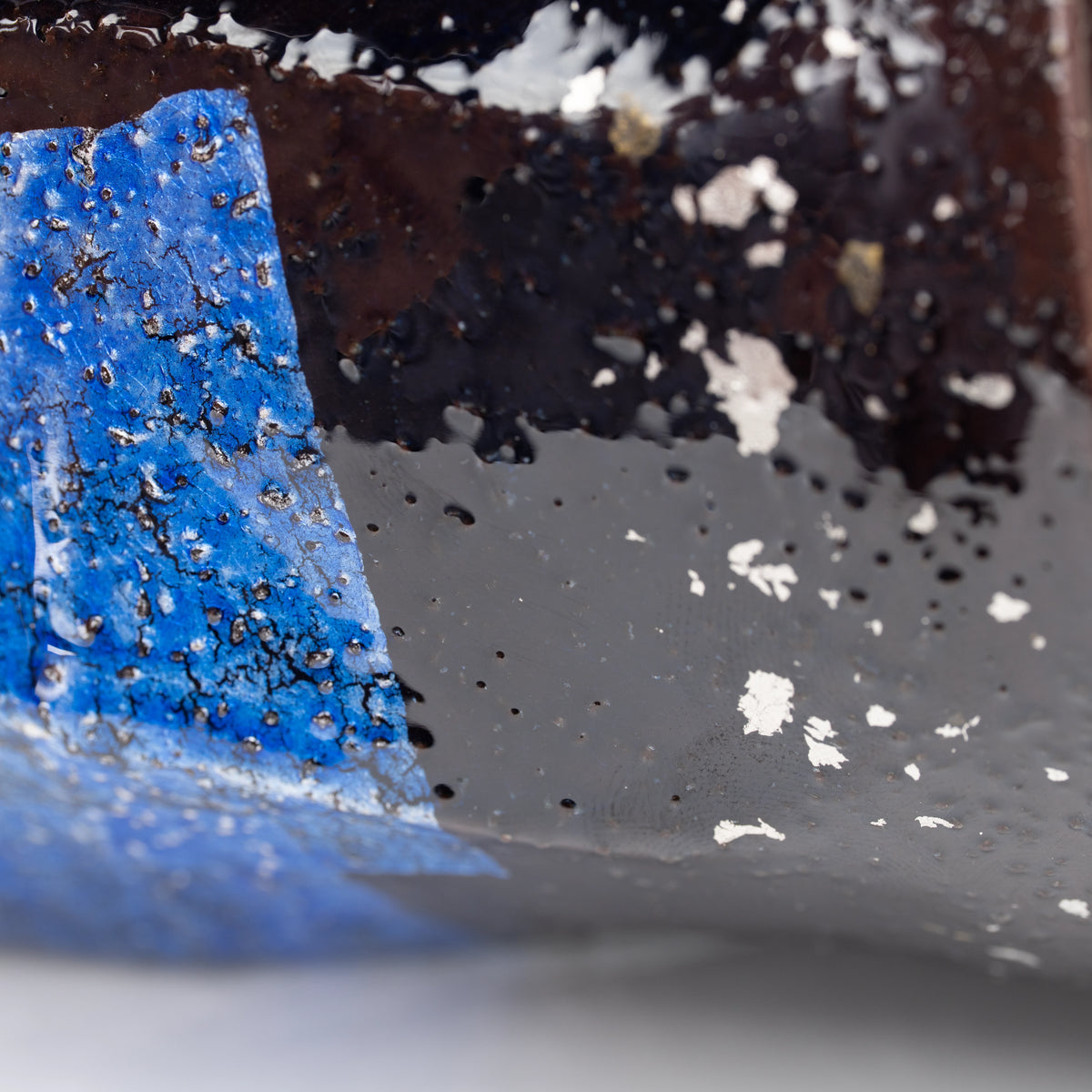 Close-up of blue, gray and black glaze with small pale flecks.