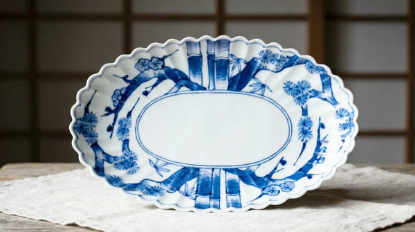 An Arita sometsuke oval platter hand-painted with bamboo and plum blossom in cobalt blue underglaze on white porcelain.