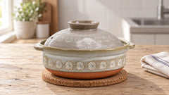 Ginpo Hana Mishima donabe with its floral lid closed, resting on a cork trivet in a home kitchen.