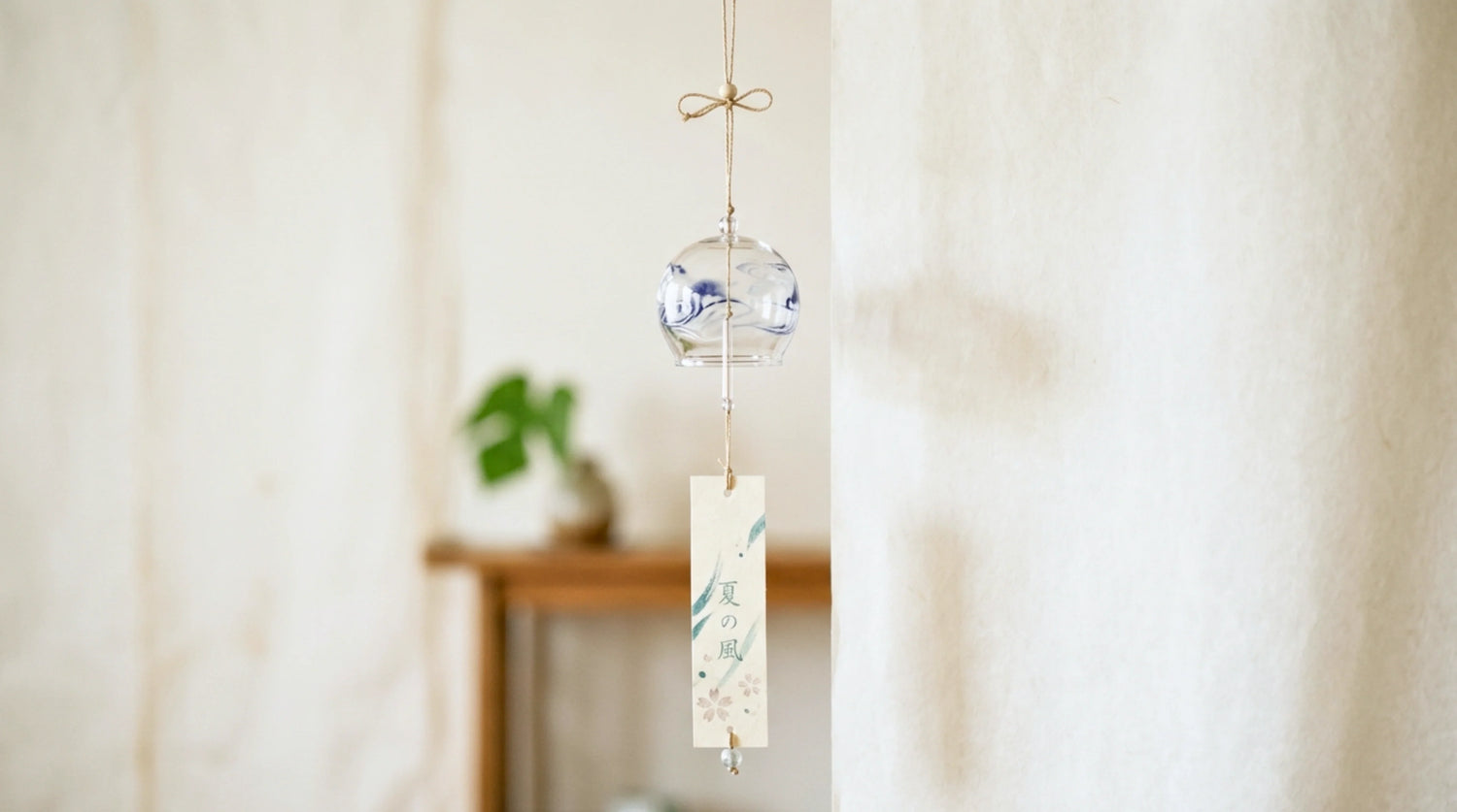 A Japanese furin glass wind chime with a tanzaku strip in a soft summer light, washi-toned scene.