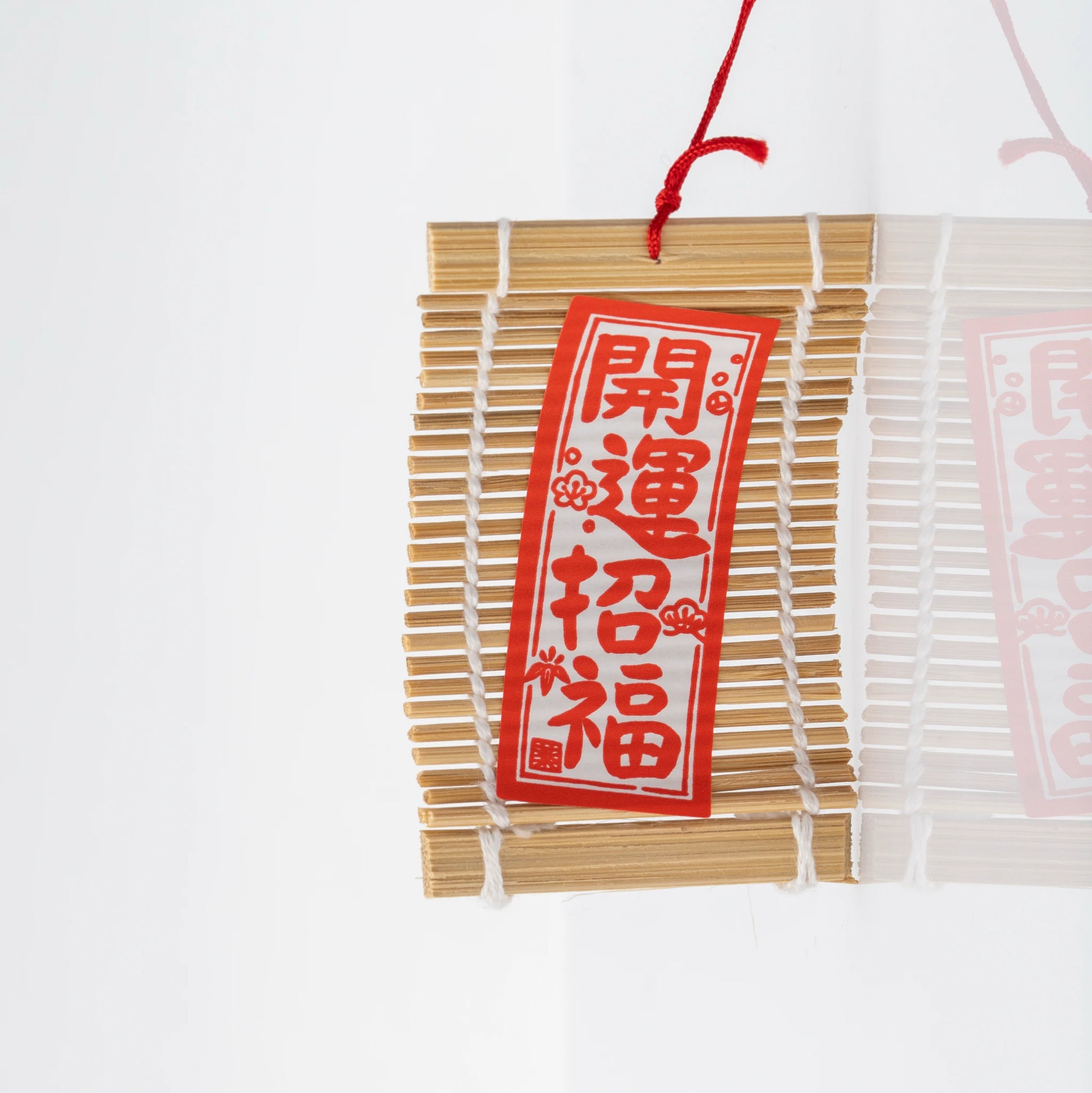 Close-up of the slatted wood wind catcher with a red paper label printed 開運招福