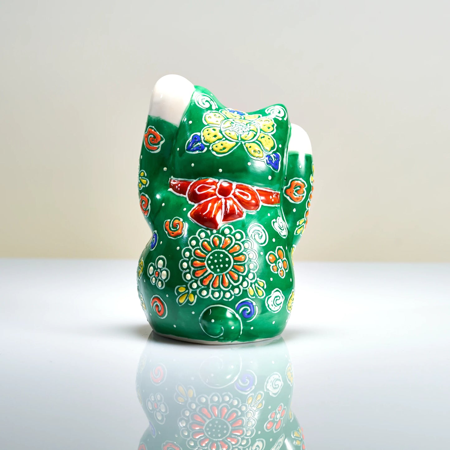Back view of the green Kutani cat featuring the red collar bow and intricate five-color (gosai) chrysanthemum rosettes.