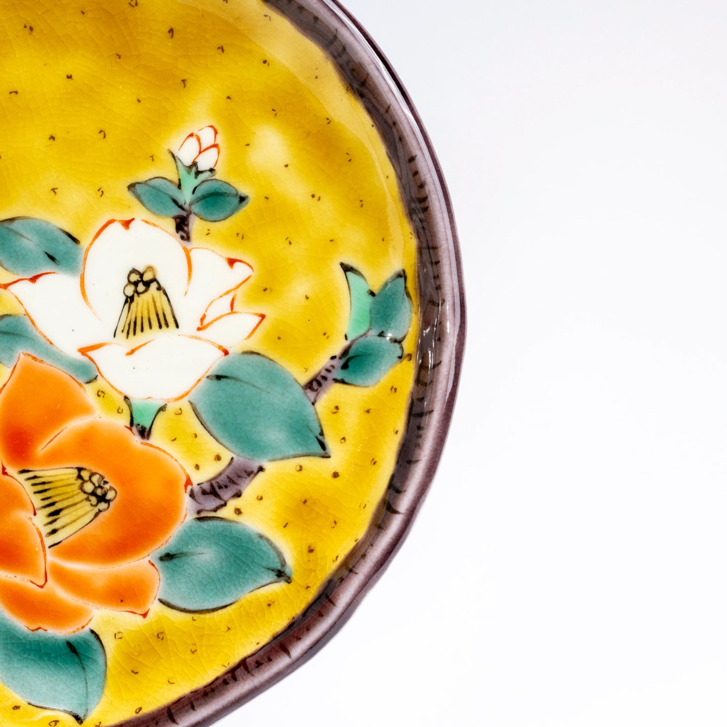 Detail view of the camellia design on a Kutani yellow dessert plate