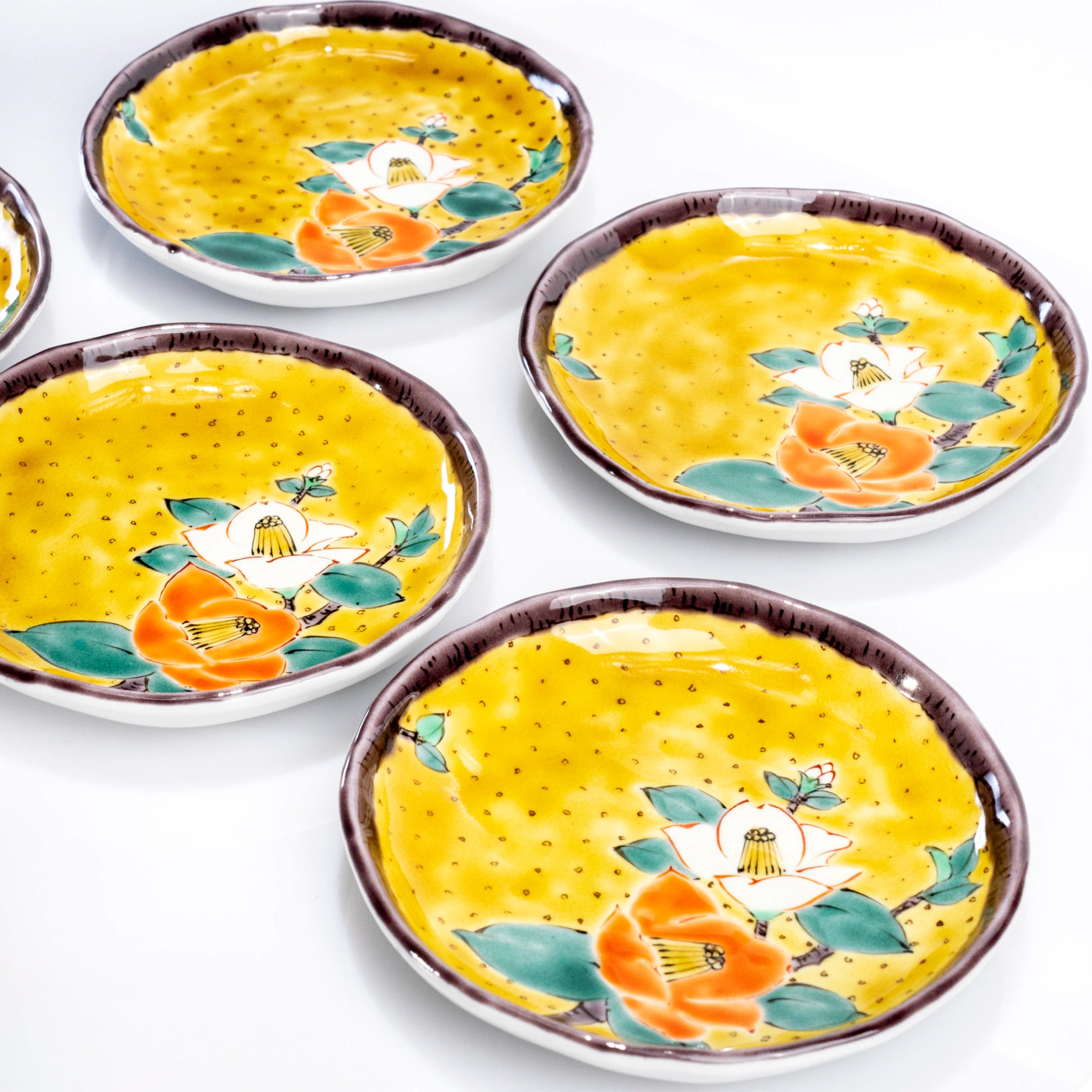 Grouped view of Kutani yellow camellia dessert plates arranged together