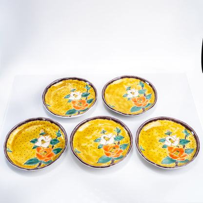 Top view of five Kutani yellow camellia dessert plates arranged together