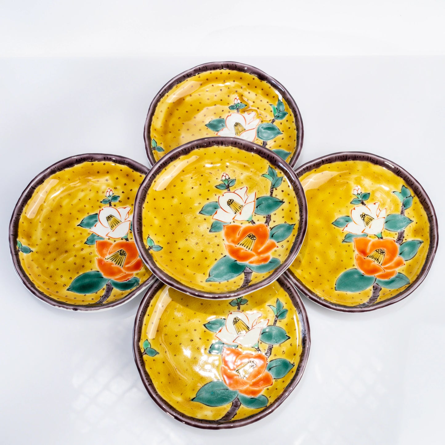 Set of five Kutani yellow dessert plates with hand-painted camellia motifs