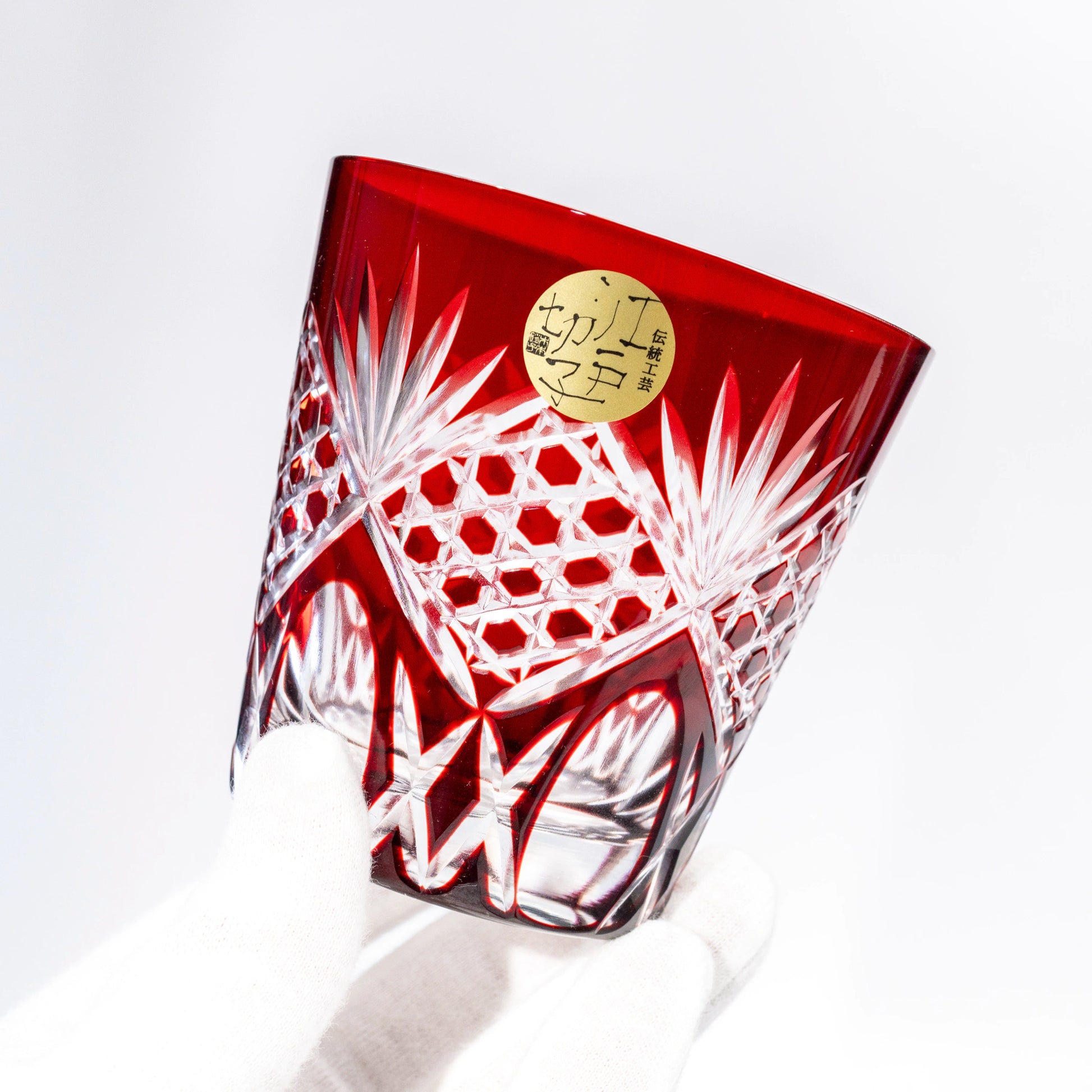 Angled view of a red Edo Kiriko whiskey tumbler showing cut-glass detail