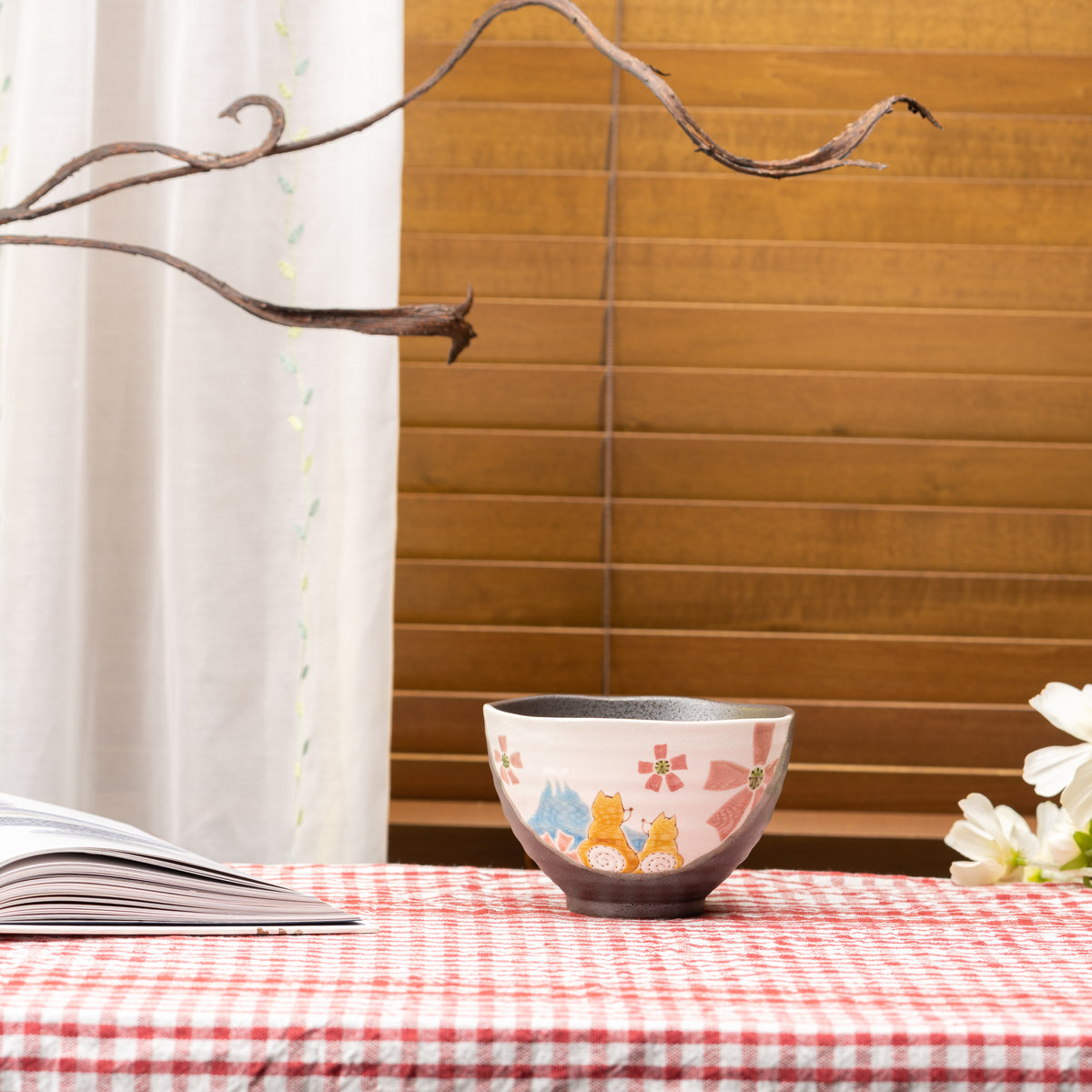 Kutani Hidamari Shiba Inu bowl with colorful dogs and flowers, displayed on a red gingham tablecloth.