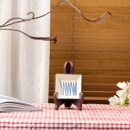 Cream Mino bowl with blue intersecting lines displayed upright on a stand on red gingham.