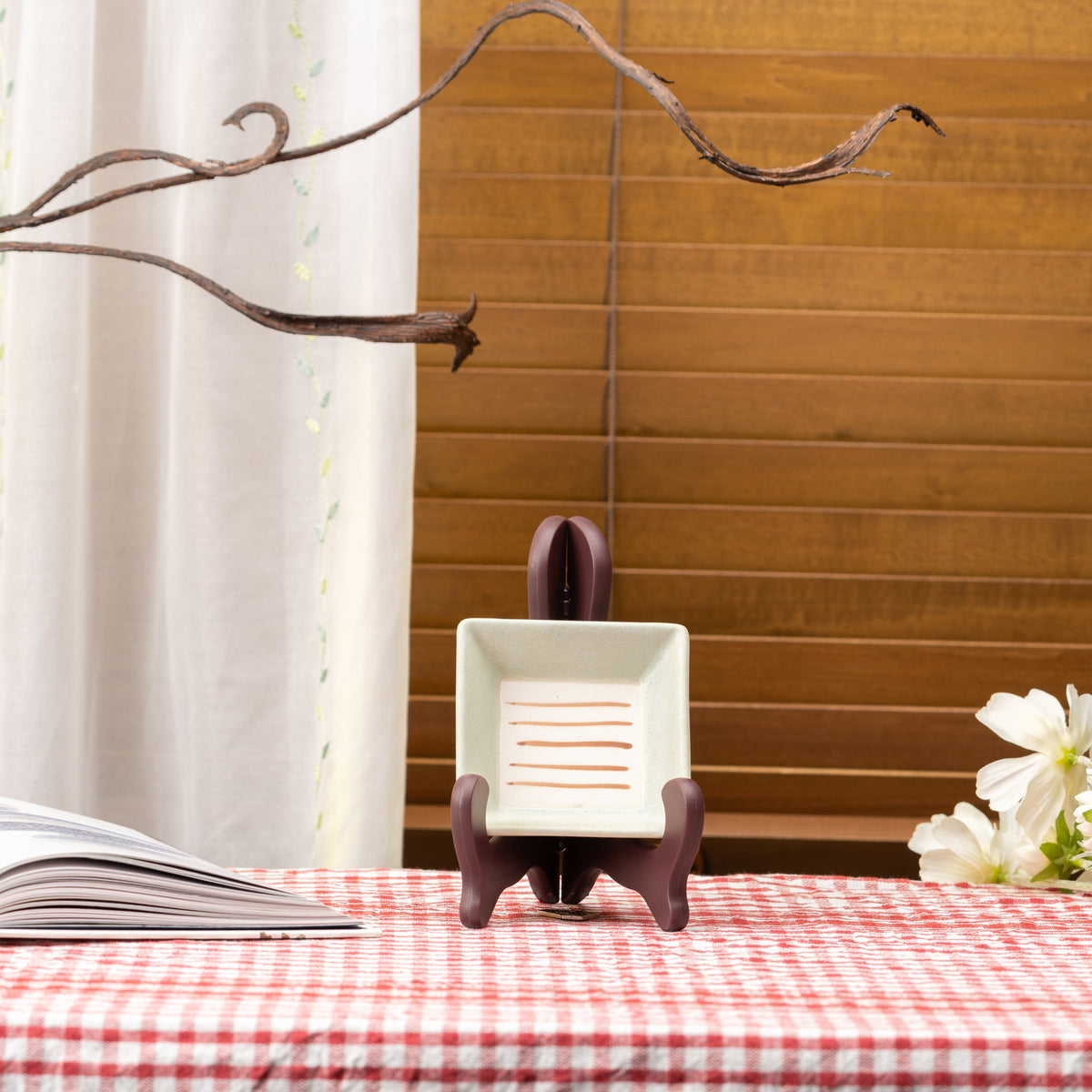 Pale Mino bowl with parallel orange lines displayed upright on a stand on red gingham.