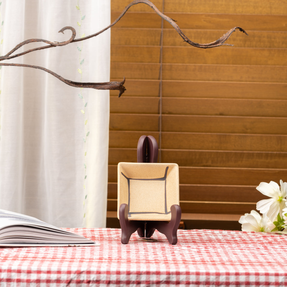 Tan Mino bowl with a dark outlined square displayed upright on a stand on red gingham.