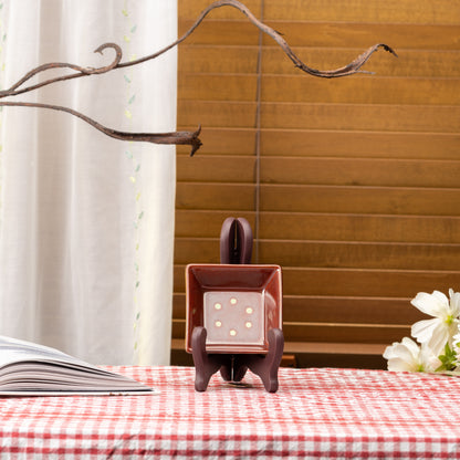 Reddish-brown Mino bowl with pale dots displayed upright on a stand on red gingham.