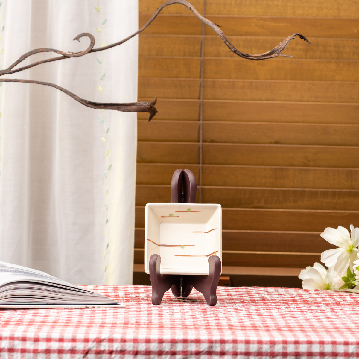 Cream Mino bowl with thin orange strokes displayed upright on a stand on red gingham.