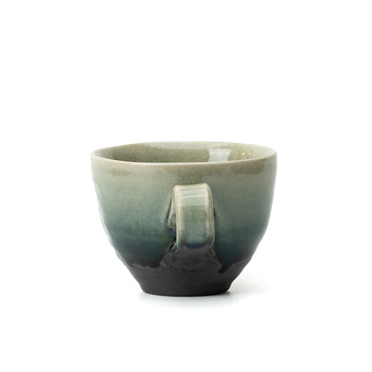Handle-facing view of the Hechimon Mosaic cup showing its green glaze and dark lower section.
