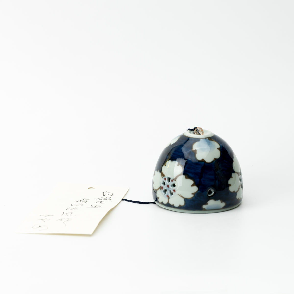 Dark blue Arita floral wind chime resting beside its paper tag on a white background.