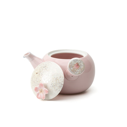Pink Sakura kyusu teapot with its blossom-topped lid removed and resting beside the open pot.