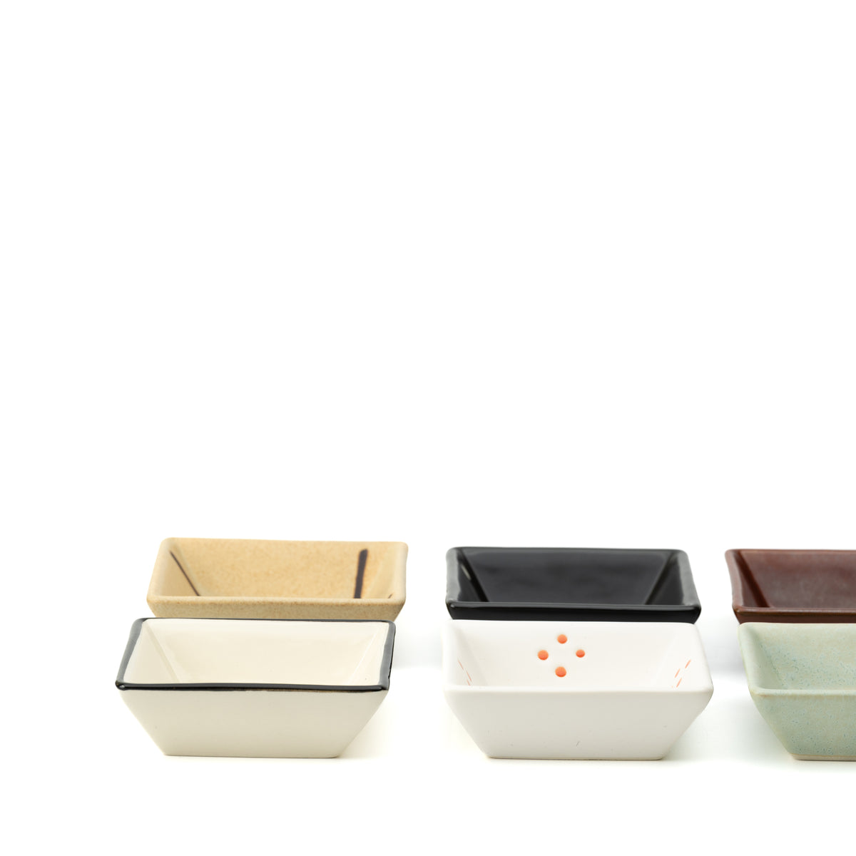 Low front view of the Mino bowl set, showing flared square sides and contrasting glazes.