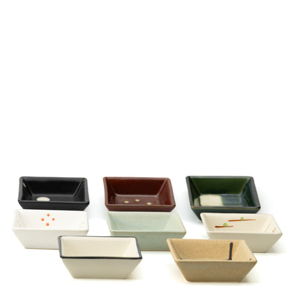Eight square Mino bowls arranged together, showing varied colors and simple geometric patterns.