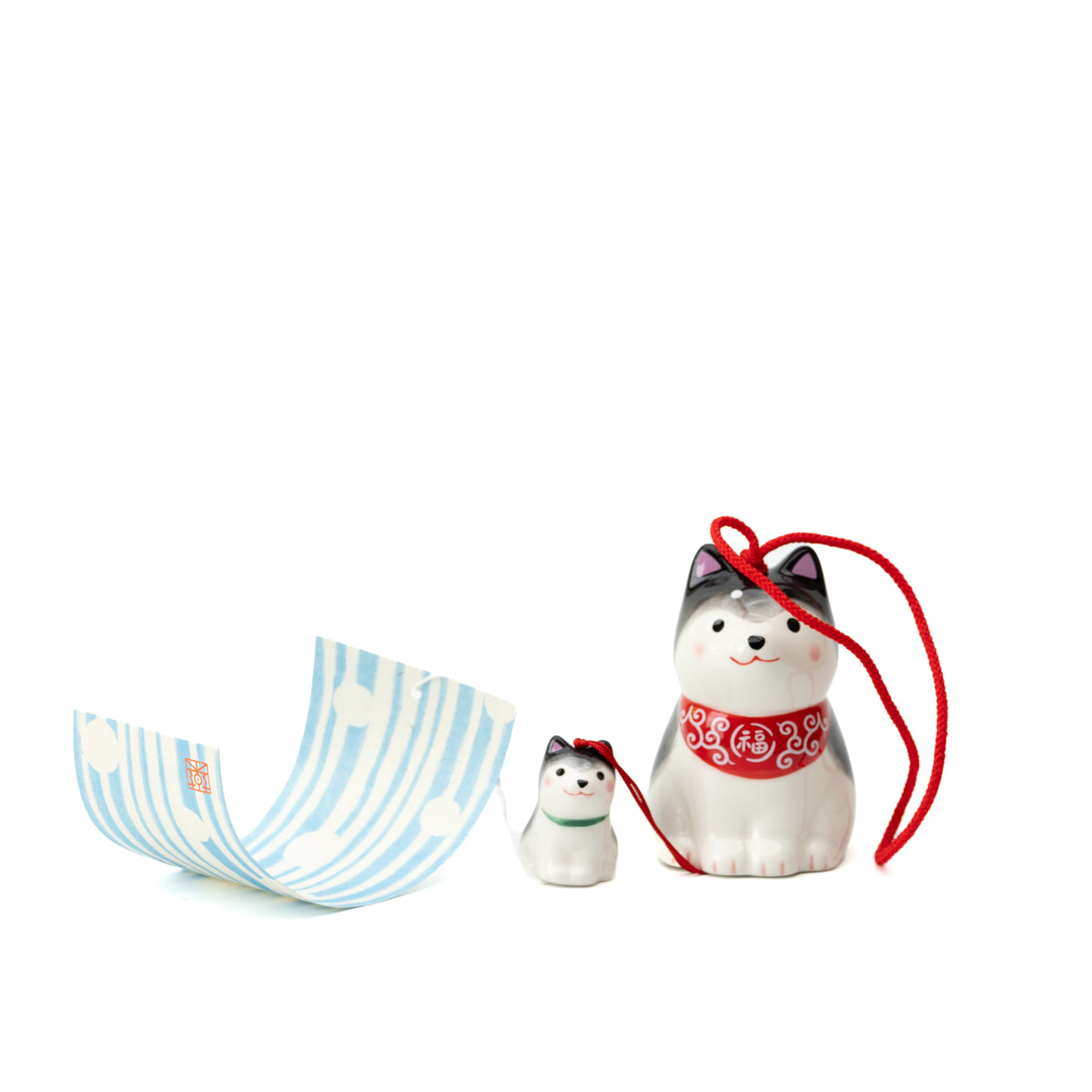 Black-and-white Shiba parent and puppy wind chime arranged beside its curled blue-striped paper tag.