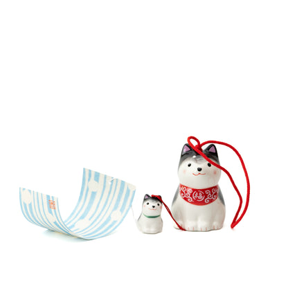 Black-and-white Shiba parent and puppy wind chime arranged beside its curled blue-striped paper tag.