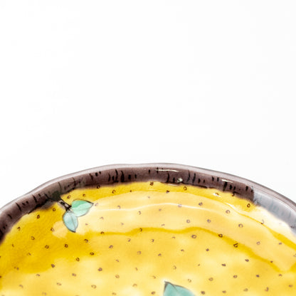 Close-up of the yellow camellia plate's dark rim and dotted yellow glaze.