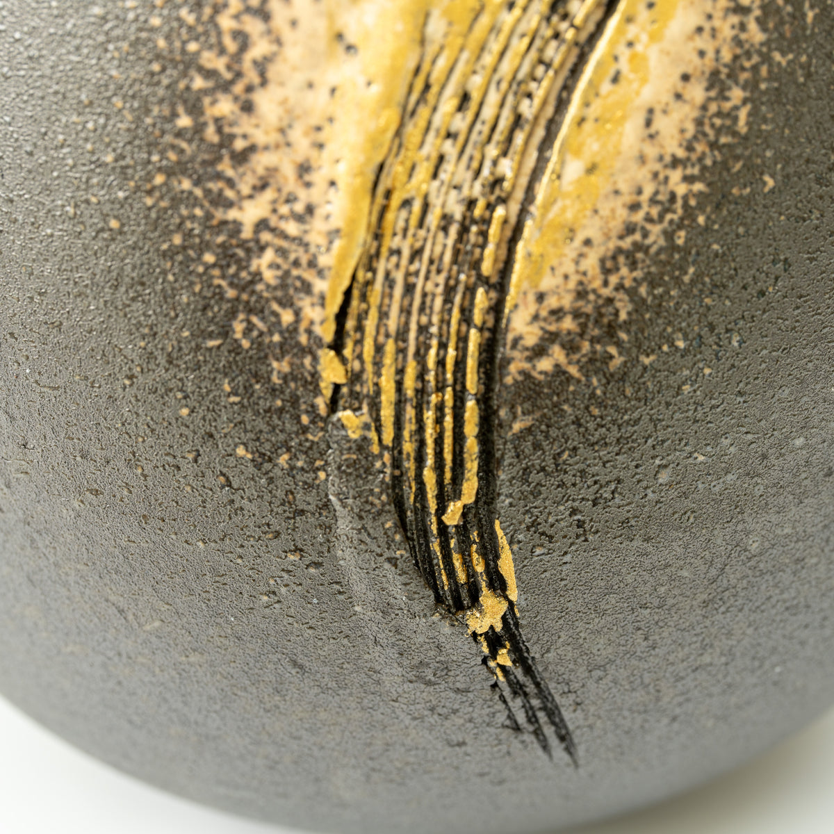 Close-up of long dark brush lines running through the Banju vase's gold-colored decoration.