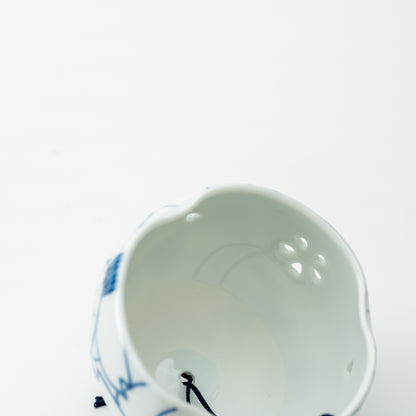 Interior of the camellia wind-chime bell, showing the pale surface, pierced openings and hanging cord.