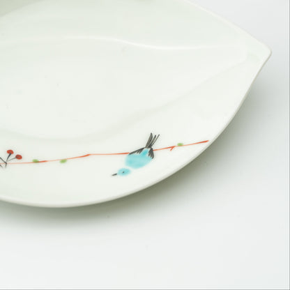 Close-up of a turquoise bird perched on a fine branch along the white leaf-shaped plate.