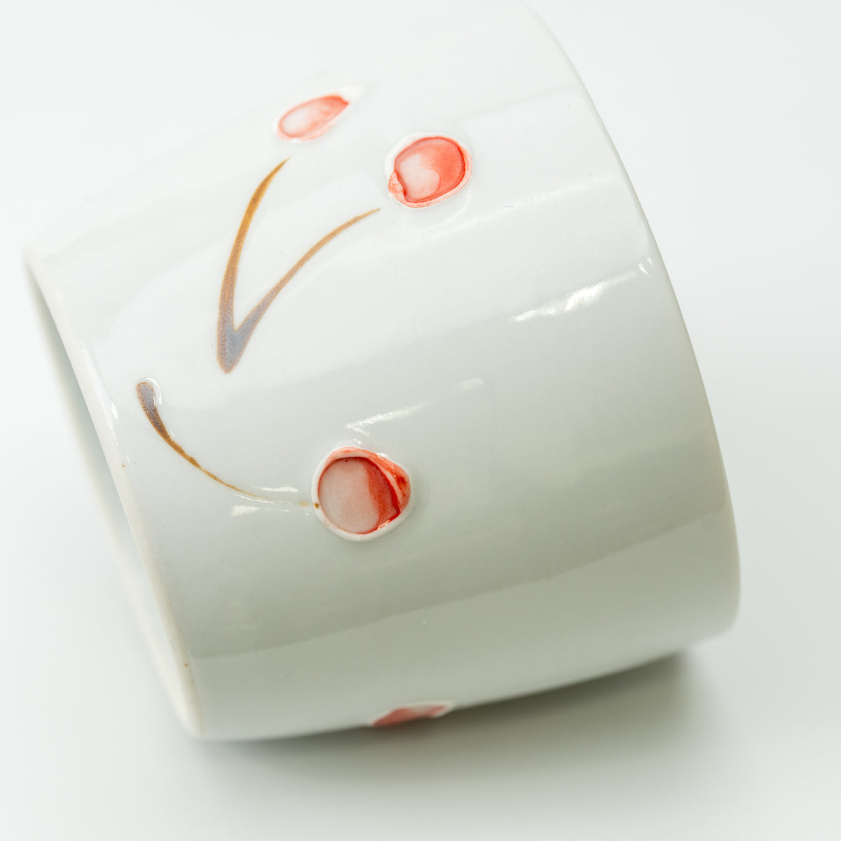 Close-up of raised pink cherries and slender stems on the white Tokushichi soba choko cup.