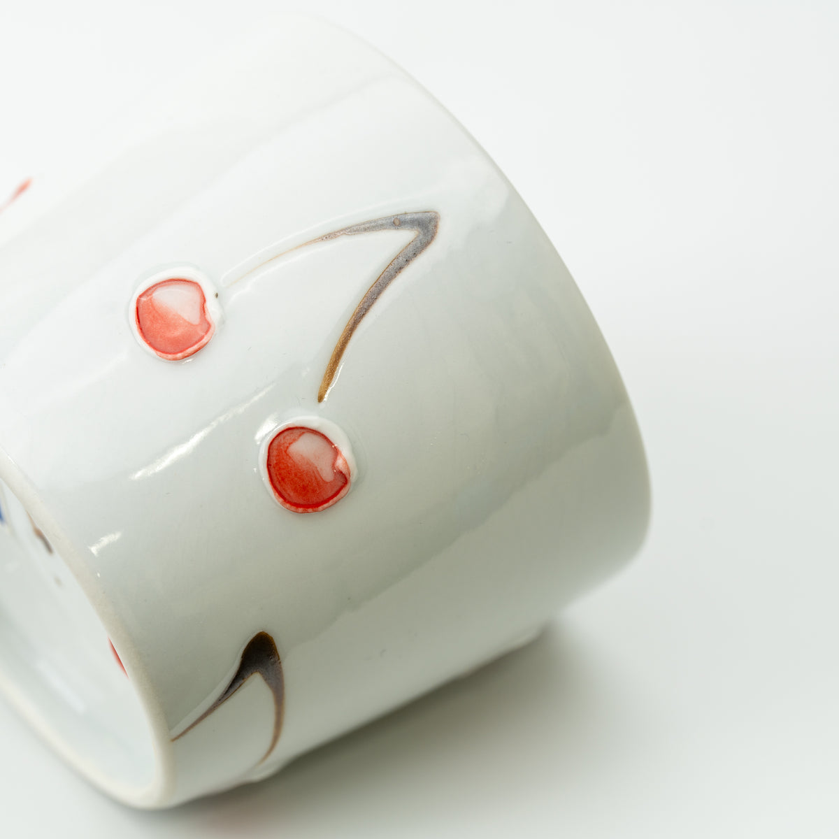 Side detail of the Tokushichi cherry cup, showing two raised pink cherries and curved stems.
