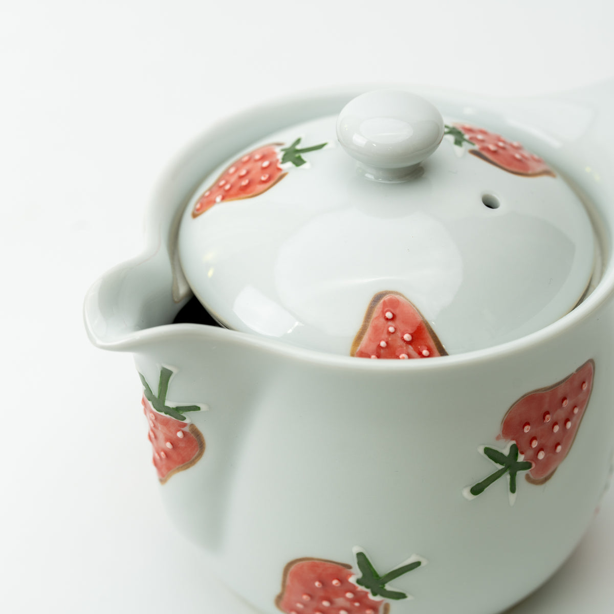 Close-up of the strawberry teapot's lid, spout and raised red strawberry decoration.