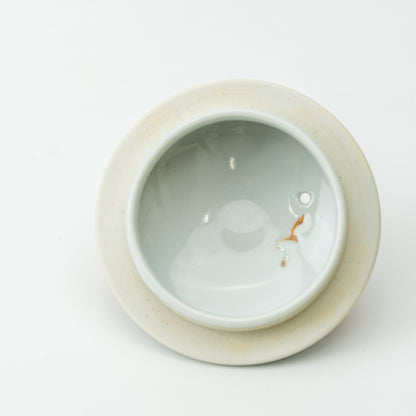 Underside of the strawberry teapot lid showing its recessed center and steam hole.