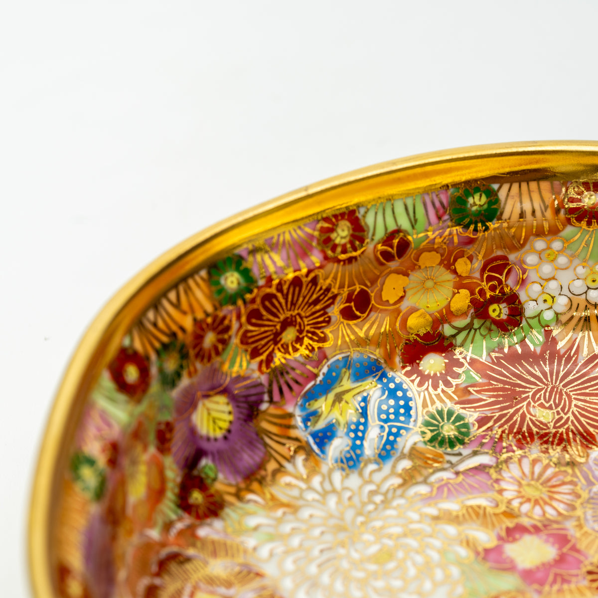 Close-up of the Kinhanazume bowl's gold-colored rim and densely patterned flowers.