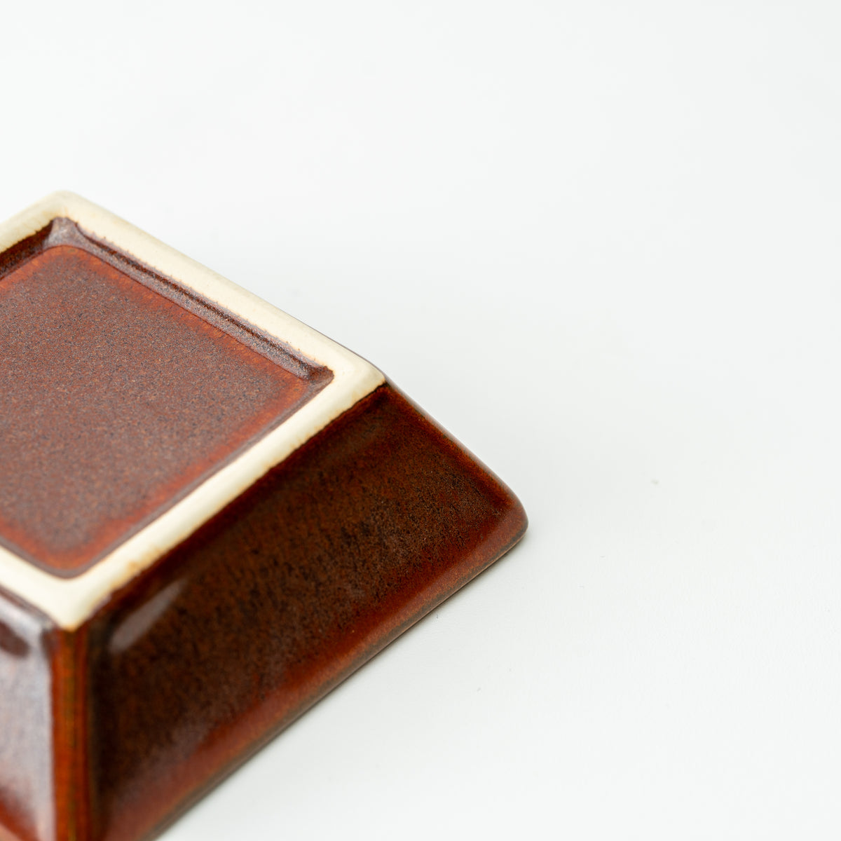 Underside corner of a reddish-brown Mino bowl with a pale square foot.